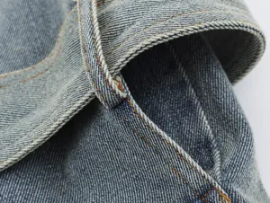 Gedetailleerd overzicht van dames blauw denim jasje met klassieke wassing en stiksels.