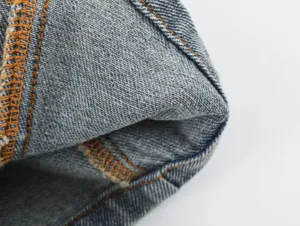 Detailopname van deninstof, close-up van blauwe denim stof met oranje stiksels.