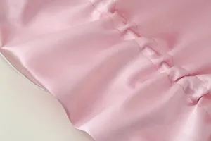 Nahaufnahme von rosafarbenem Satin mit feinen Raffdetails und glatter, eleganter Textur.