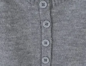 Gray knit cardigan button detail, close-up shot showing fine texture and matching buttons.
