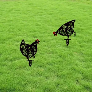 Detailed view of black acrylic rooster garden stakes with floral cutouts on a green lawn.
