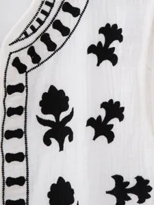 Close up view of the exquisite black embroidery on white fabric, delicate detail shot for vest.