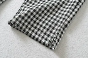 Black and white gingham plaid pattern pants hem cuff detail shot showcasing side split design.
