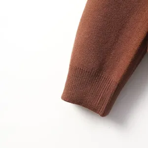 Close-up view of a brown knitted sweater sleeve cuff, showcasing fine ribbed texture details.