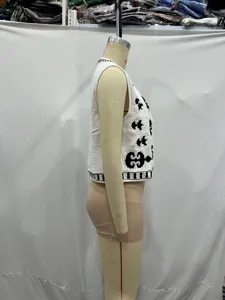 Side detail view of the white sleeveless crop vest featuring bold black ethnic embroidery.