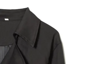 Close-up detail of black trench coat collar, showcasing neat stitching and premium fabric.