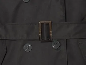 Detailed view of the women's black trench coat featuring a stylish belt buckle and buttons.