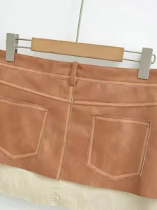 Detailed shot of retro pu leather spliced contrast color mini skirt, stylish back pocket design.