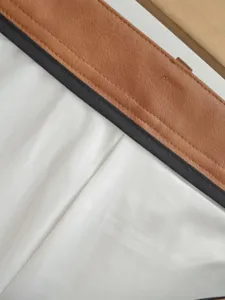 Detail shot of womens PU leather spliced short skirt, contrast black trim, fine stitching.
