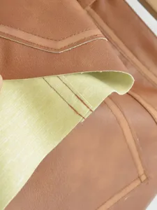 Close-up detail of vintage PU leather skirt featuring contrast stitching and lining texture.