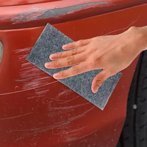 Detailed shot of nano car scratch repair cloth in use, polishing red paint surface.