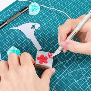 Close up of craft vinyl weeding tool and carving knife in action on green cutting mat.