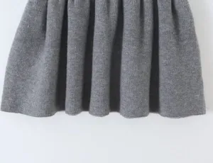 Detailed view of grey knitted pleated skirt, showcasing fine texture and elegant design.
