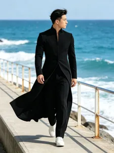 Vue détaillée du manteau noir à col montant porté par un mannequin sur la jetée côtière.