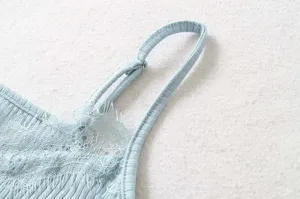 Close-up detail of light blue ribbed knit camisole strap and delicate lace trim design.