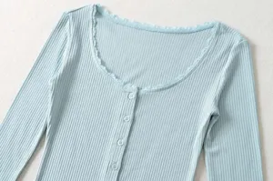 Close-up detail of light blue ribbed knit long sleeve top with delicate lace scoop neck.