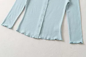 Ribbed knit cardigan detail view, showing soft fabric texture, buttons and cute ruffled cuffs.
