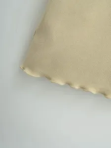 Detailaufnahme des feinen gerippten Strickstoffs mit zartem Rollsaum in hellem Beigeton.
