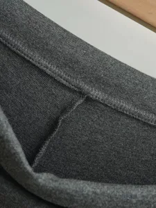 Nahaufnahme des weichen dunkelgrauen Strickstoffs mit sauberer Naht und hochwertiger Textur.