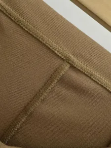Nahaufnahme von braunem Rippstoff mit sauberer Naht, zeigt feine Stricktextur und Qualität.