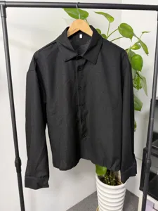 Detailed shot of men's textured black long-sleeve loose lapel shirt hanging on rack.