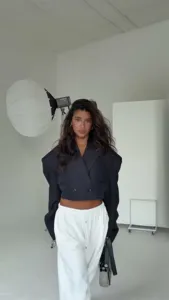 Dettaglio del elegante blazer nero oversize abbinato a comodi pantaloni casual bianchi.