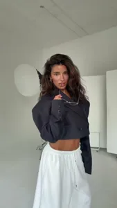 Blazer nero corto e pantaloni sportivi bianchi, dettaglio look autunnale chic e casual.