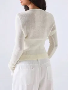 Detailed back view of a solid color knitted cardigan top worn by a model in white pants.