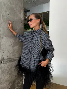 Detailed view of women's grey plaid oversized shirt with stylish black feather hem trim.