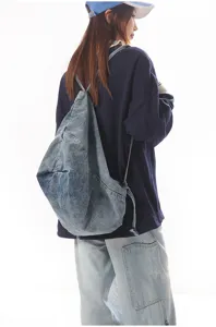Close-up view of the casual denim drawstring backpack showing soft slouchy fabric and straps.