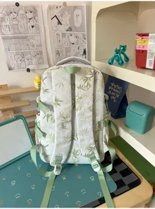 Detailed view of green bamboo leaf print casual backpack on clean desk setup with cute props.