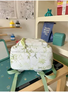 Detail view of the white backpack featuring green bamboo leaf and bird print pattern.