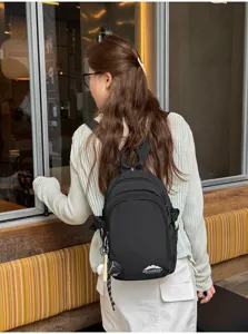 Detailansicht des lässigen Nylon-Minirucksacks in Schwarz mit Anhänger und Fronttasche