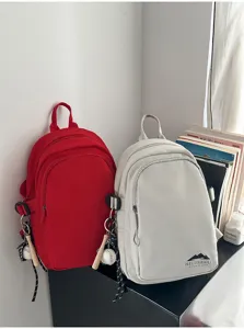 Lässiger minimalistischer Nylon Mini Rucksack für Damen, leichte Umhängetasche mit Baseball Anhänger.