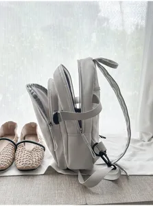 Detailansicht eines hellgrauen Freizeitrucksacks mit mehreren Fächern und Reißverschlüssen.