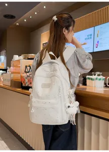 Detailansicht des weißen Sternenhimmel-Schulrucksacks mit süßem Anhänger für den Schulalltag.