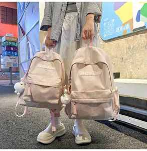 Close-up detail of the pink holographic school backpack with cute bear pendant for daily commute.