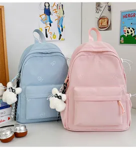 Detailed shot of pastel school backpack featuring cute bear embroidery and fluffy bunny charm.