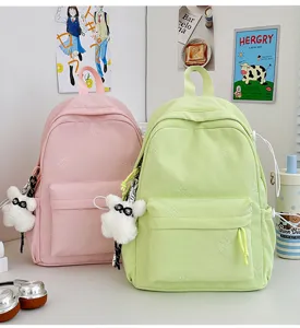 Detailed shot of cute pastel school backpacks with embroidered bears and plush pendant.