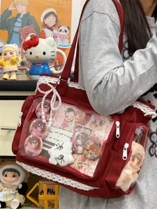 Red canvas ita bag featuring clear window, lace trim, and pearl chain for daily commute.