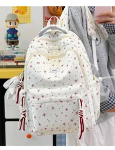 Detail view of a white canvas school backpack featuring cute red star prints and spacious pockets.