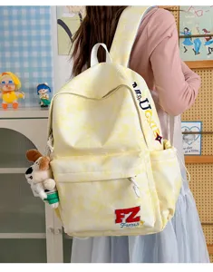 Detail shot of yellow tie-dye canvas backpack with cute plush pendant and front pocket design.