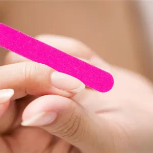 Close up view of a vibrant pink sandpaper nail file in action, showing fine texture and smooth grip.