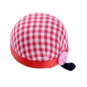 Close-up detail of red white gingham wrist pin cushion with pink button and elastic strap.