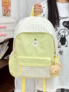 Detailaufnahme des süßen ästhetischen gelben Karo-Schulrucksacks mit Apfel-Stickerei und Plüsch.