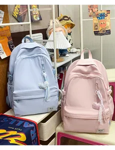 Detailed view of casual student backpacks in pastel blue and pink with cute heart pendants.