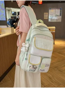 Detailed shot of the cute multi-pocket green canvas student backpack with plaid flap and charm.