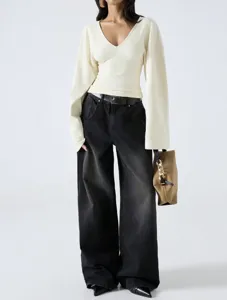 Detailed view of beige V-neck long sleeve top with flared sleeves and black wide-leg pants.