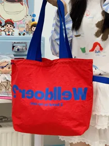 Detail shot of the red canvas tote bag with blue straps, large capacity daily commuting.