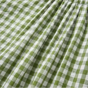 Green and white checkered fabric detail, soft woven material texture and gathered pleat close-up.